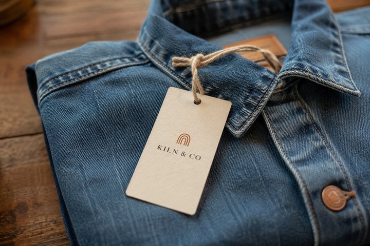 Custom hang tag with brand logo attached to a folded denim jacket for an apparel brand
